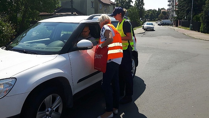Akcja ulotkowa - przedstawiciele kampanii wręczają materiały informacjne kierowcy w samochodzie