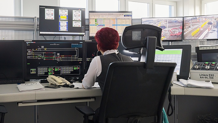 Kobieta przy biurku przed kilkoma ekranami z systemami w budynku LCS