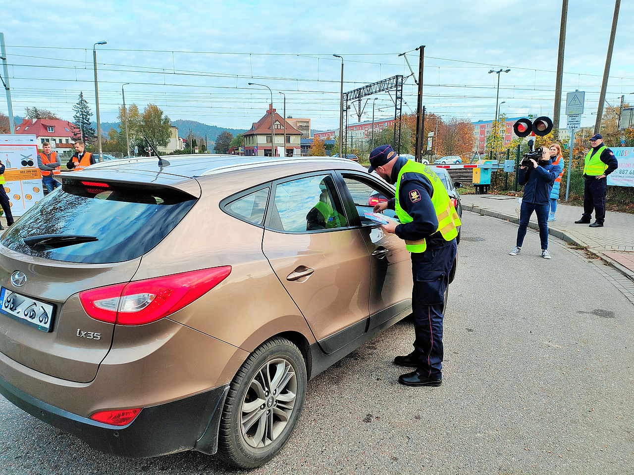 Samochód przed przejazdem kolejowo-drogowym, funkcjonariusz SOK wręcza ulotkę kierowcy 2 fot. Przemysław Zieliński PKP PLK
