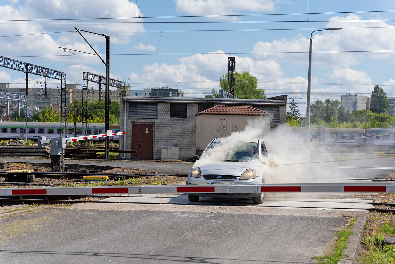 Samochód unieruchomiony na przejeździe z którego wydobywa się dym.