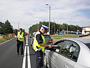 Policjant wręcza ulotkę kierowcy 