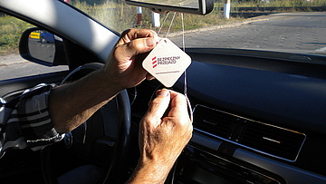 Zbliżenie na dłonie kierowcy samochodu trzymające kampanijny gadżet.