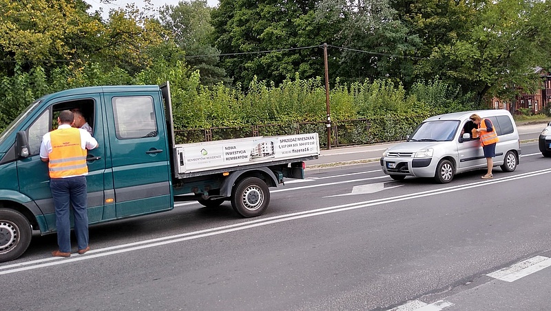 Samochody przed zamkniętym przejazdem. Kierowcy otrzymują materiały od koordynatorki kampanii.