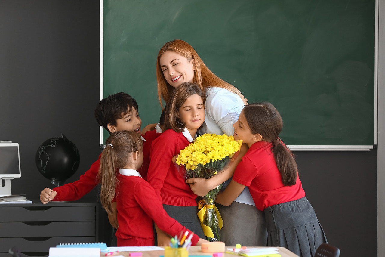 Nauczycielka z kwiatami pośród 4 dzieci.