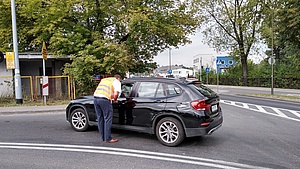 Przedstawiciel kampanii wręcza ulotkę kierowcy w samochodzie