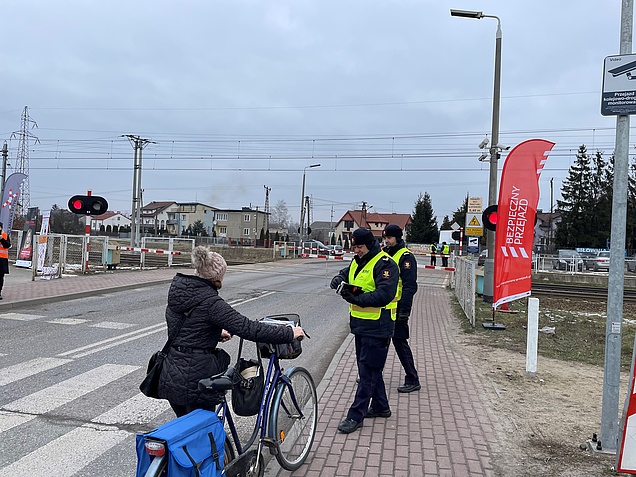 Funkcjonariusze Straży Ochrony Kolei wręczają ulotki rowerzystce przed przejazdem kolejowo-drogowym w Siedlcach; fot. Anna Znajewska-Pawluk