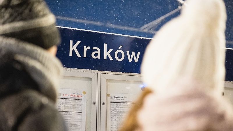 Widok na parę stojącą przed tablicą z rozkładem jazdy