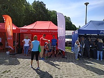 Czerwony namiot kampanijny wraz z osobami odwiedzającymi to stoisko.