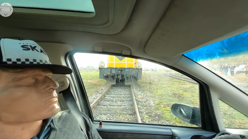 Manekin w samochodzie, w tle nadjeżdżająca lokomotywa.