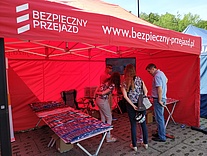 Czerwony namiot kampanijny wraz z osobami odwiedzającymi to stoisko.