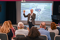Marcin Kruszyński podczas prezentacji. W ręku trzyma bezpiecznik rogatki.