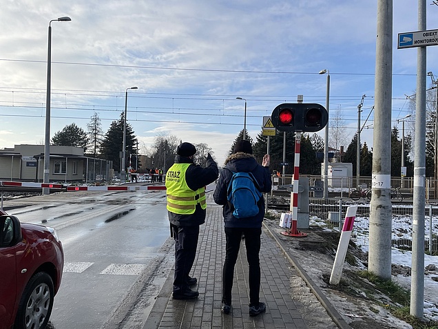 Akcja ulotkowa na przejeździe kolejowo-drogowym w Nowej iwicznej, przedstawiciel SOK udziela informacji pieszemu fot. Anna Znajewska Pawluk