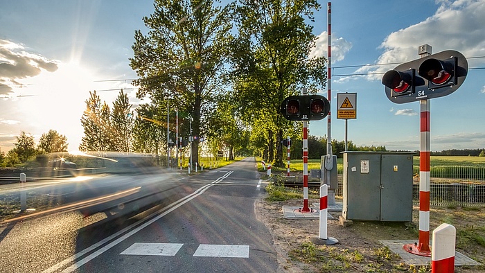 Przejazd kolejowo drogowy. Z lewej strony rozmazany pojazd w ruchu.