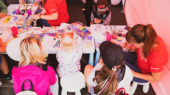 Dzieci przy stoliku z materiałami edukacyjnymi i plastycznymi. 
