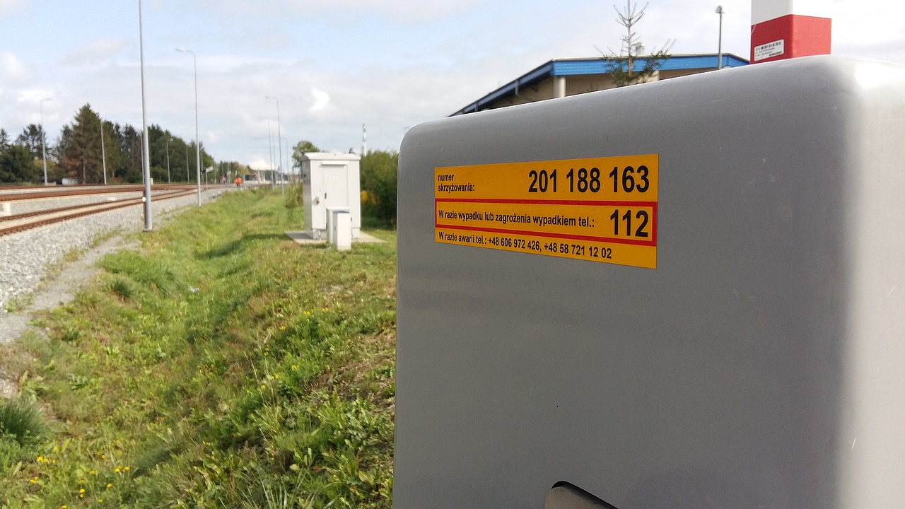Zbliżenie na żółtą naklejkę PLK na napędzie rogatki