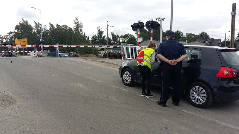Przedstawiciele kampanii wręczają materiały informacyjne kierowcy w samochodzi przed przejazdem