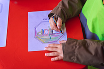 Zbliżenie na kolorujące kartkę ręce dziecka.