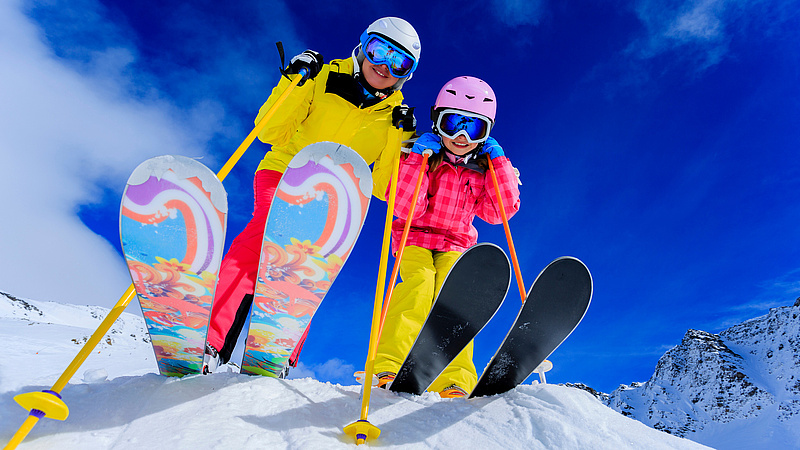 Zdjęcie od dołu, dwójka młodych narciarzy.