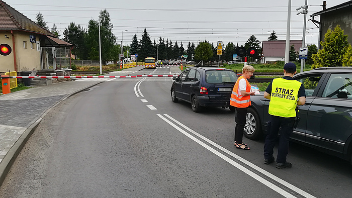 Samochody przed zamkniętym przejazdem. Kierowcy otrzymują materiały od sokisty i koordynatorki kampanii.