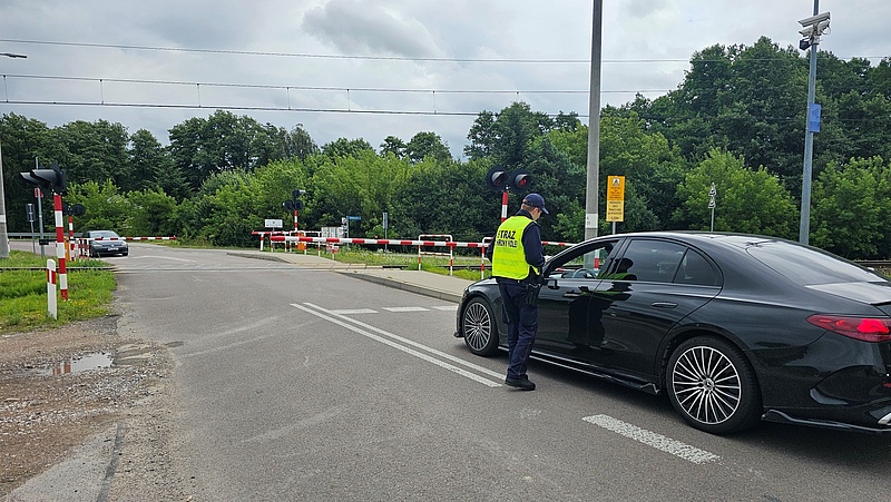 Sokista wręcza ulotkę kierowcy oczekującemu przed zamkniętym szlabanem